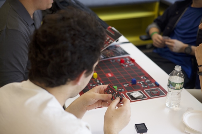 Close-up photo taken over the shoulder of a Tisch Summer High School Game Design student playing a board game during a game design class.